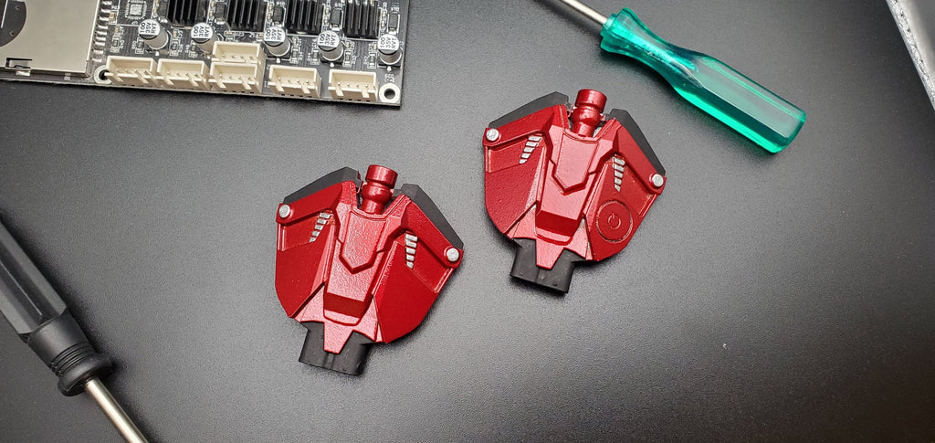 MaskOryx TASM2 web shooter replica props in metallic red with black details, displayed on a dark workbench.